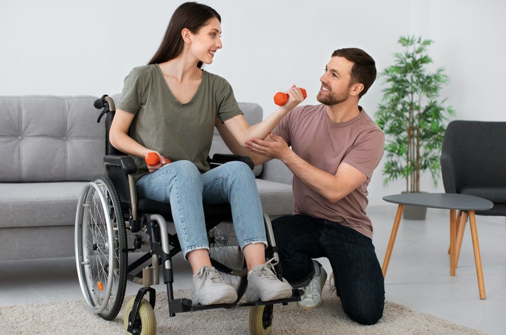 iBCare support worker helping a wheelchair user with exercises at home